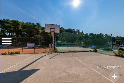 Košarkarsko igrišče poleg območja za odbojko na mivki pod jasnim nebom